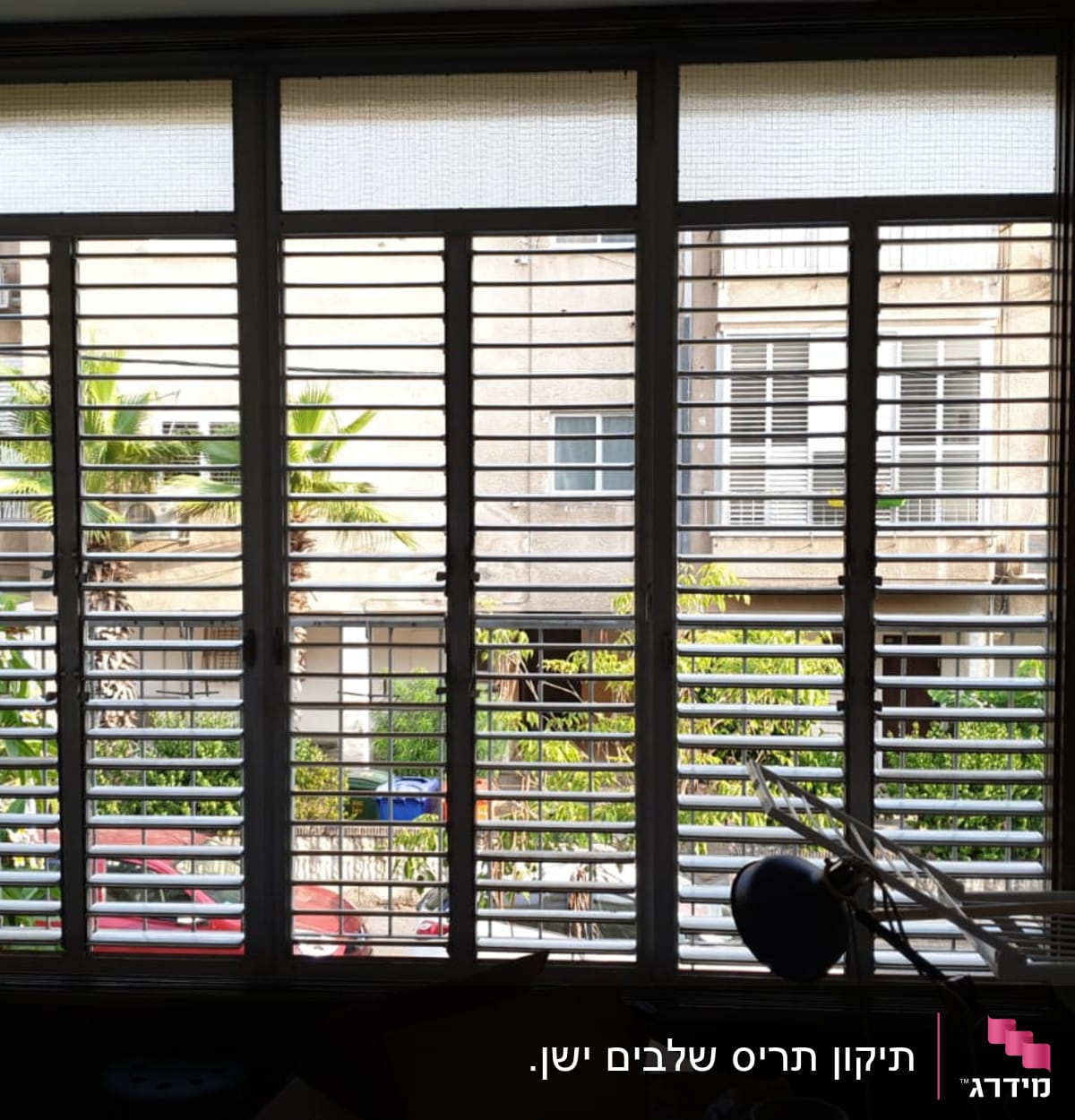 תריסים אופקיים על חלון גדול עם נוף חיצוני